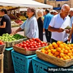 몰타어 기초 회화 - A vibrant and bustling outdoor market scene in a historic town square in Malta. The square is paved ...